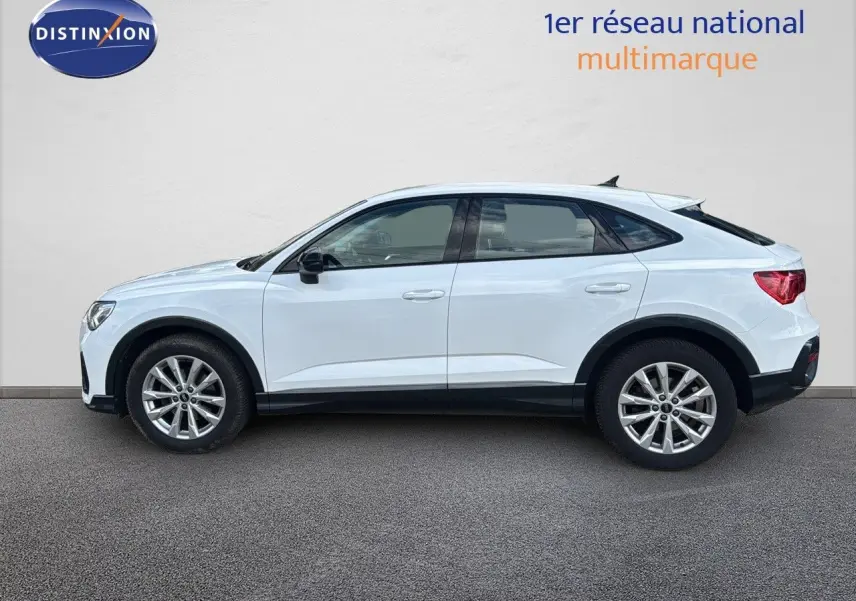 Profil côté gauche d'un Audi Q3 Sportback blanc de 2021 avec jantes alliage et toit plongeant distinctif.
