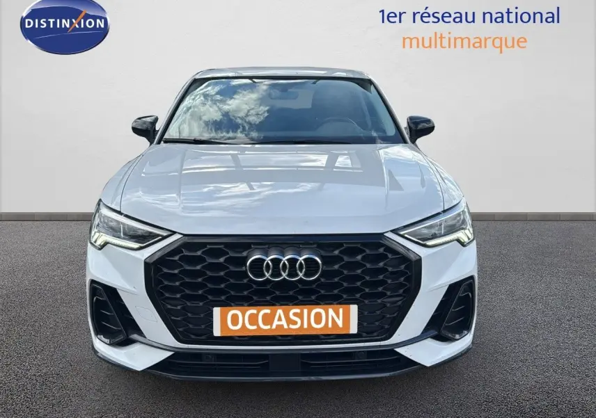 Vue frontale d'un Audi Q3 Sportback blanc 2021 avec calandre noire et phares LED allumés.