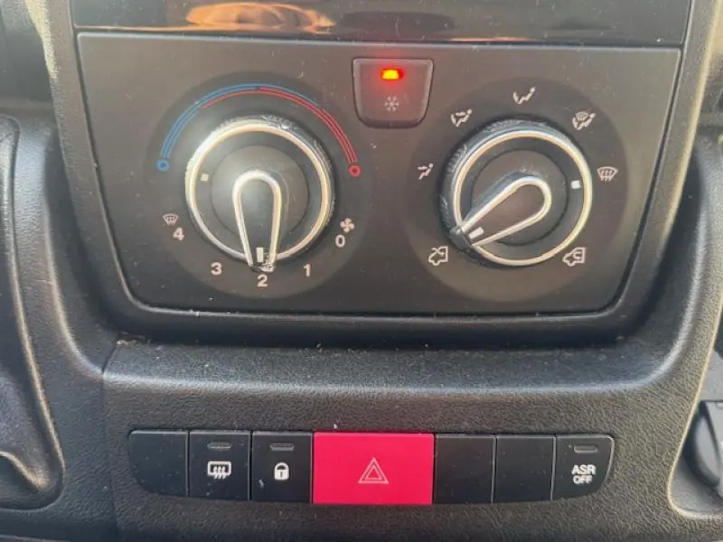 Panneau de commande de climatisation et boutons de sécurité dans le Peugeot Boxer Fourgon blanc, vue rapprochée intérieure.