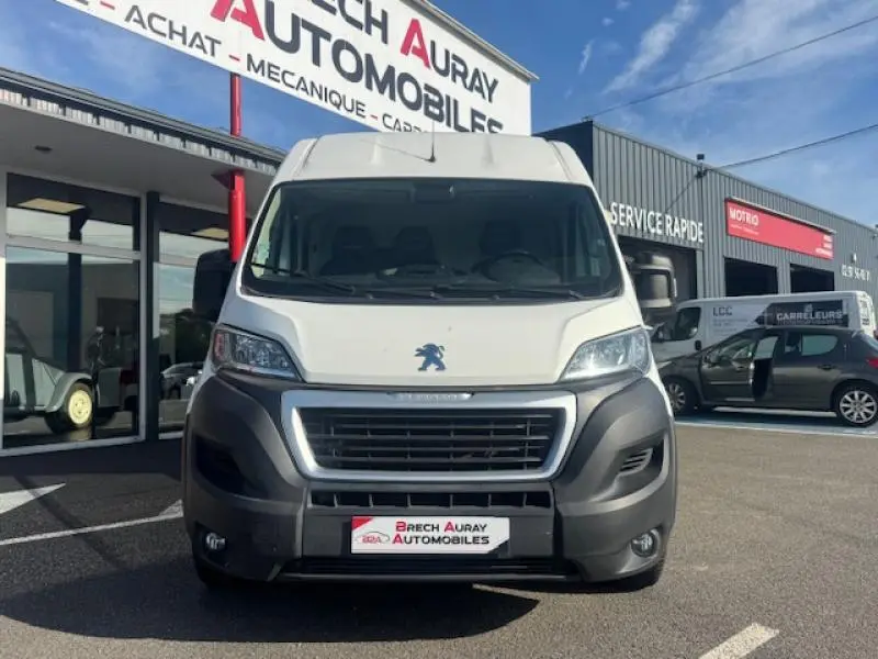 Vue frontale d'un Peugeot Boxer Fourgon blanc Banquise stationné devant un garage automobile.