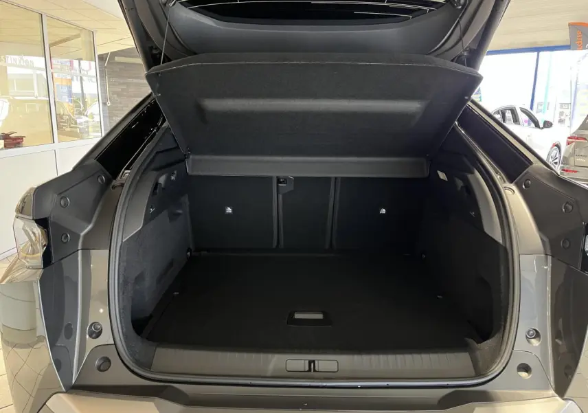 Coffre ouvert vu de l'arrière d'un Peugeot 3008 gris titanium, montrant l'espace de chargement vide.