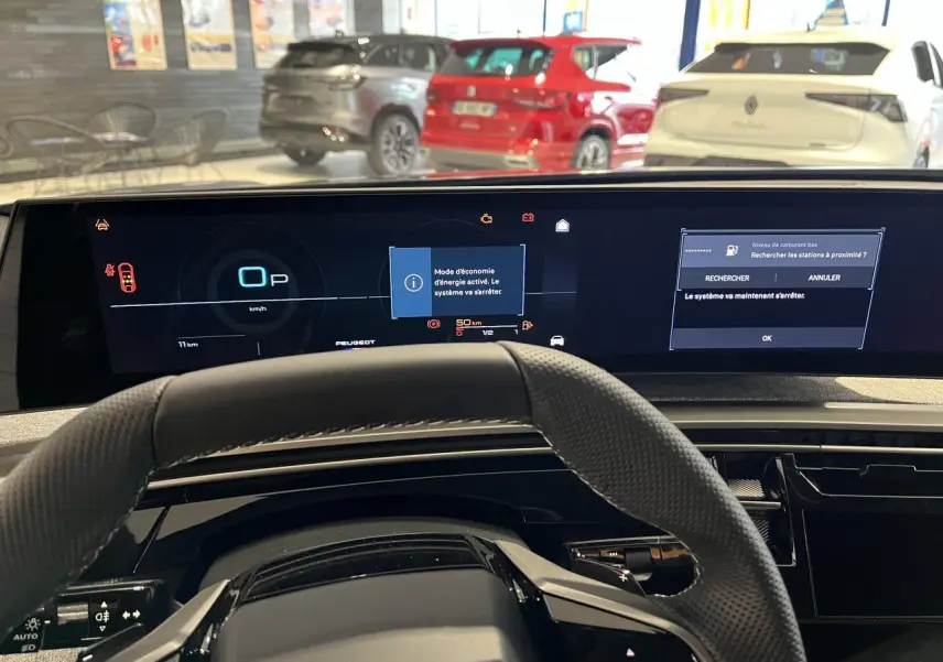 Vue intérieure du tableau de bord et volant du Peugeot 3008 gris titanium 2025, avec écran numérique panoramique allumé.