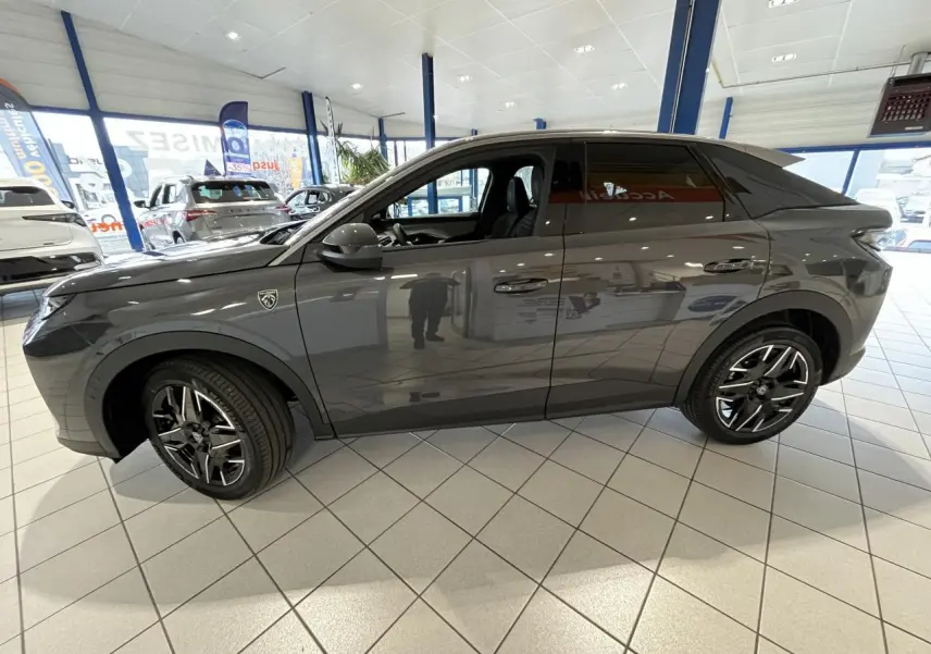 Vue de profil côté gauche d’un Peugeot 3008 gris titanium avec jantes alliage noires et badge GT visible sur l’aile avant.