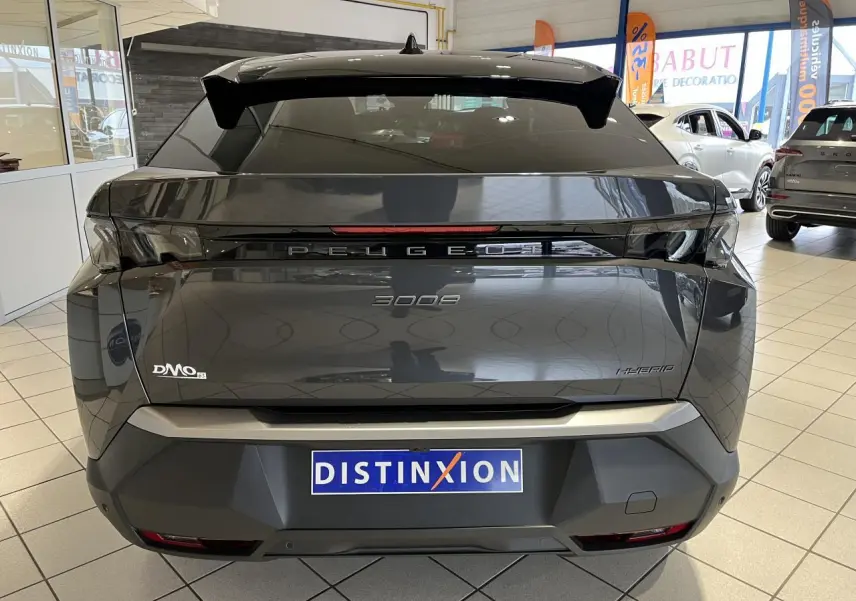 Vue arrière d'un Peugeot 3008 gris titanium hybride, avec bandeau noir laqué entre feux et logo Peugeot visible.