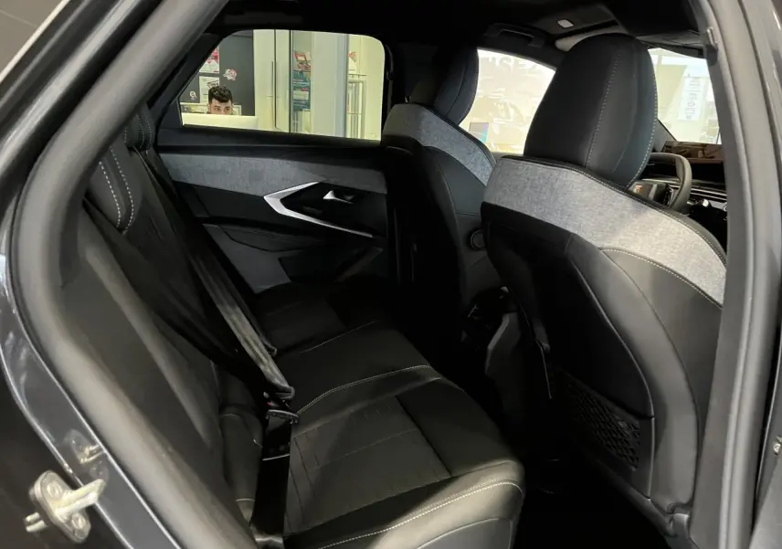 Vue intérieure côté gauche des sièges arrière et avant du Peugeot 3008 gris titanium, sellerie tissu et cuir noir avec surpiqûres claires.
