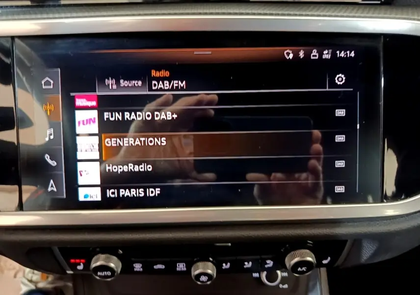 Écran tactile central de l’Audi Q3 35 TFSI S Line 2022 affichant les stations radio DAB/FM en intérieur noir.