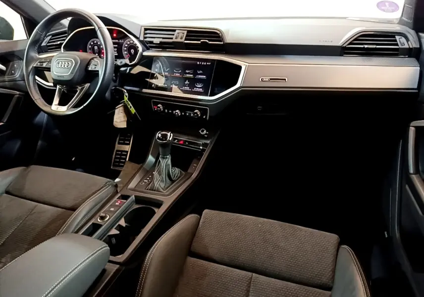 Vue intérieure côté conducteur de l'Audi Q3 35 TFSI S Line 2022 avec tableau de bord noir et écran tactile central.