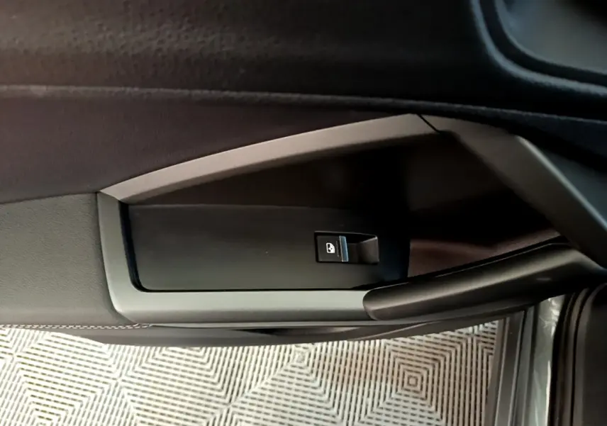 Détail de la commande de verrouillage des portes sur la portière côté gauche d’un Audi Q3 gris foncé.