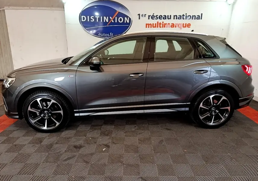 Vue latérale droite d’un Audi Q3 gris foncé 35 TFSI S LINE avec jantes noires et feux arrière allumés.