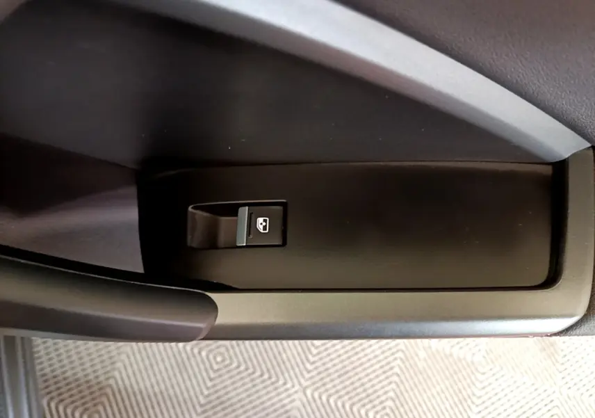 Gros plan sur le bouton de commande de la vitre électrique côté conducteur dans l'habitacle noir de l'Audi Q3 gris foncé.