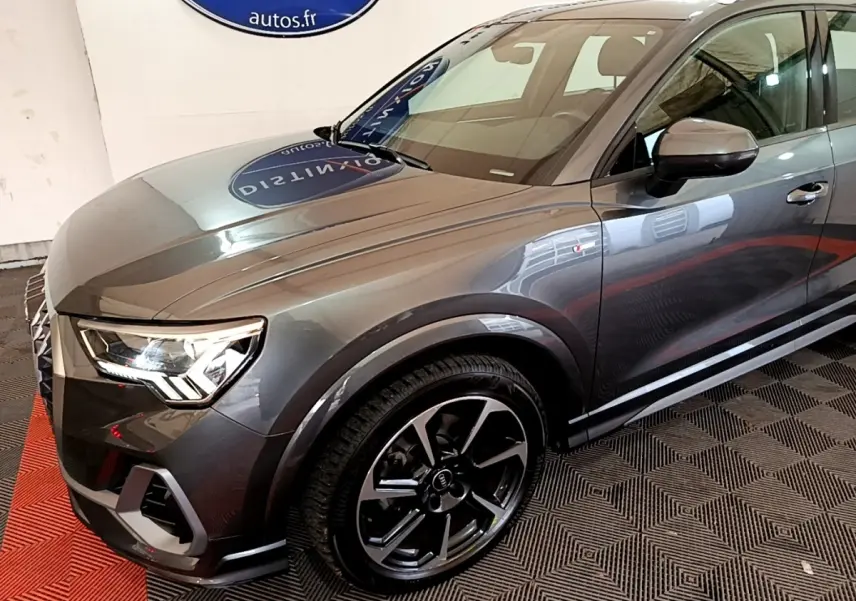 Audi Q3 gris foncé vue 3/4 avant droit, mettant en valeur ses phares LED et jantes noires distinctives.