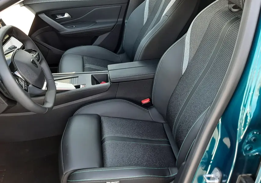 Vue intérieure côté conducteur de la Peugeot 308 2026 bleu obsession, sièges en cuir et tissu avec surpiqûres contrastées.