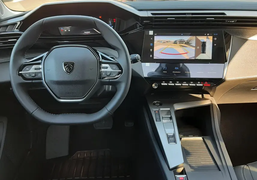 Vue intérieure centrée sur le volant et la console centrale de la Peugeot 308 2026, avec écran tactile affichant la caméra 360°.