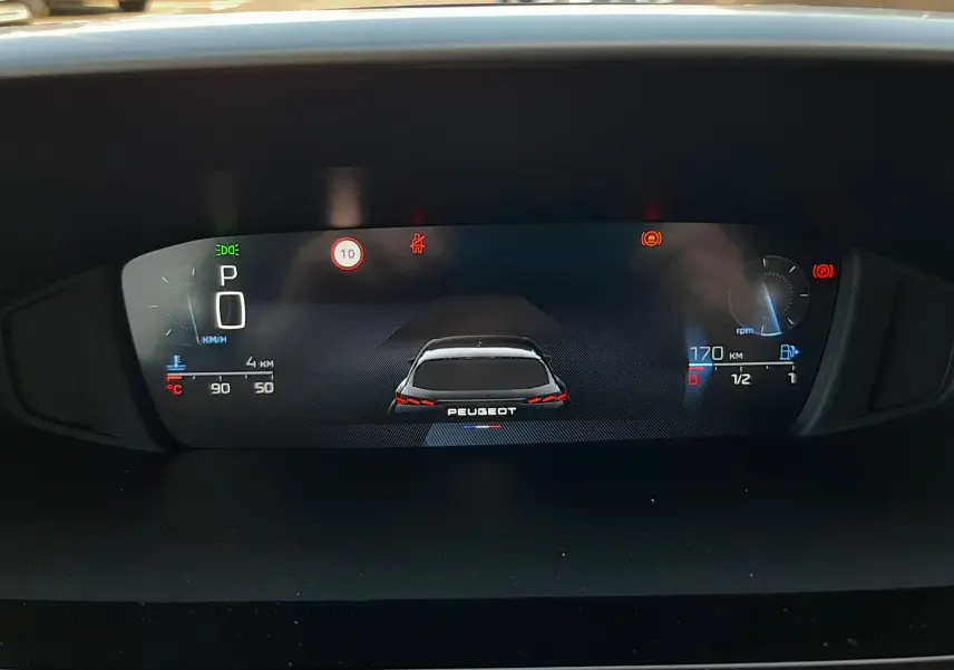 Affichage numérique du tableau de bord de la Peugeot 308, montrant un véhicule vu de l'arrière et les indicateurs de vitesse et carburant.