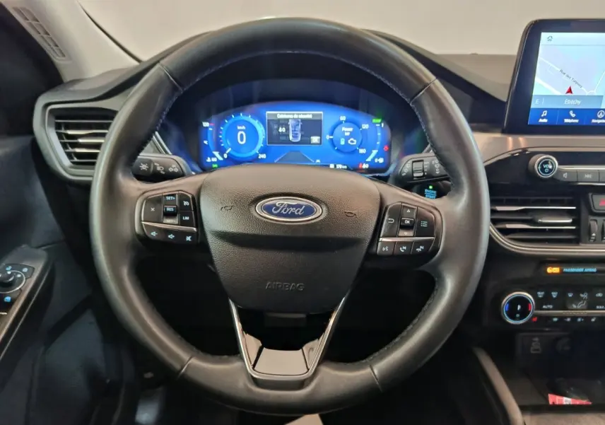 Vue intérieure centrée sur le volant cuir noir du Ford Kuga 2023 avec tableau de bord numérique et écran tactile.