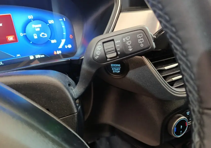 Gros plan intérieur sur le combiné d'instruments bleu et la commande des essuie-glaces du Ford Kuga 2023.