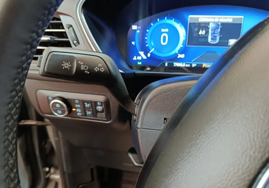 Gros plan sur le volant et le combiné d'instruments numérique bleu du Ford Kuga 2023, version hybride.