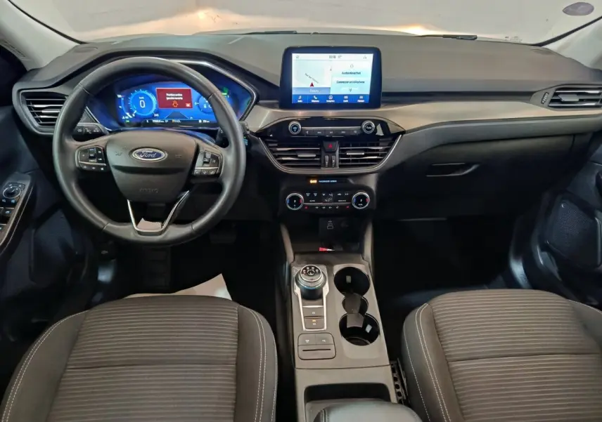 Vue intérieure frontale du tableau de bord et volant cuir du Ford Kuga 2.5 hybrid Titanium avec écran tactile central.