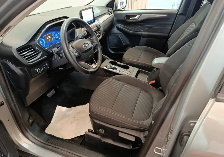 Intérieur avant droit du Ford Kuga gris foncé 2023, avec tableau de bord numérique et volant multifonctions.