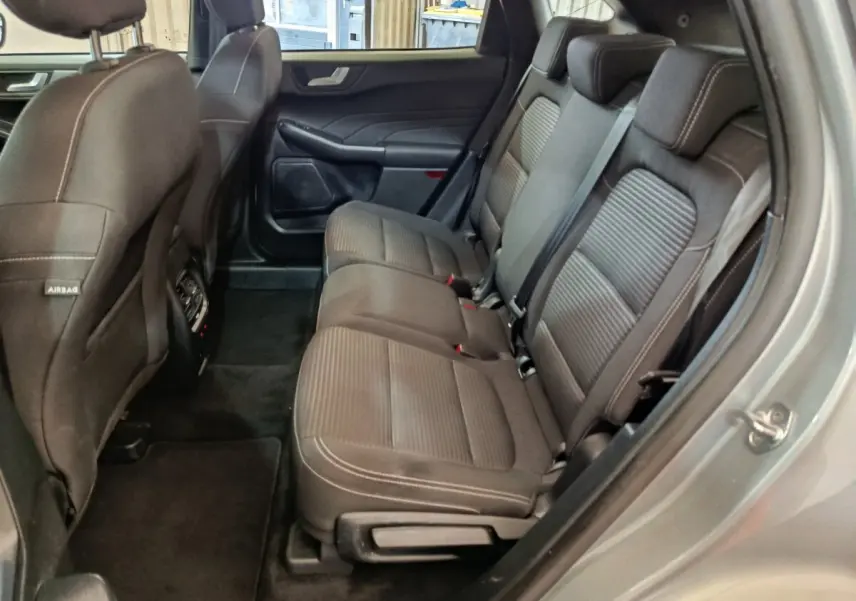 Vue intérieure côté droit montrant la banquette arrière en tissu gris foncé du Ford Kuga 2023 hybride.