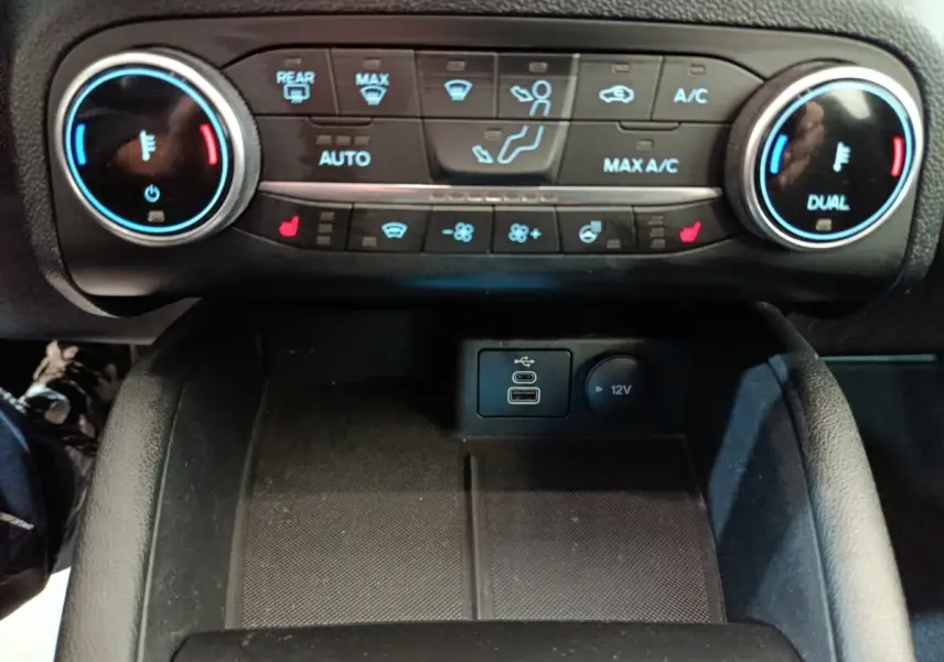 Vue rapprochée du tableau de bord central du Ford Kuga 2023, montrant les commandes de climatisation et ports USB.