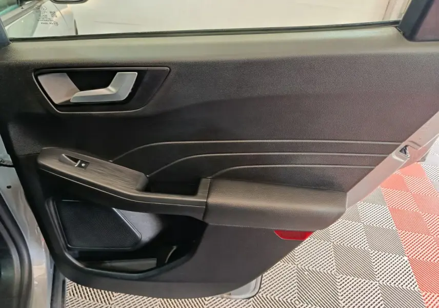 Vue intérieure de la porte avant gauche du Ford Kuga gris foncé, avec poignée argentée et commande de vitre.