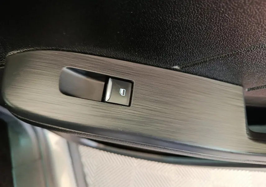 Gros plan sur le bouton de commande de la vitre électrique côté conducteur du Ford Kuga gris foncé, finition Titanium.