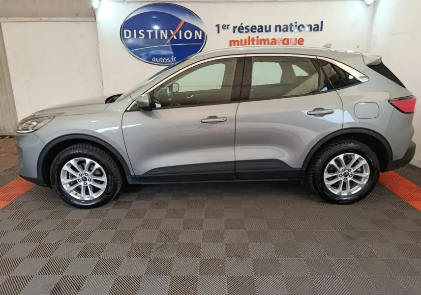 Vue de profil côté gauche d'un Ford Kuga gris foncé 2023 avec jantes alliage et barres de toit chromées.