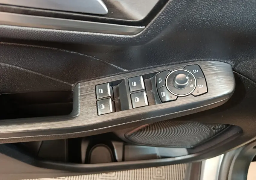 Gros plan sur la commande des vitres et rétroviseurs côté conducteur du Ford Kuga gris foncé 2023.