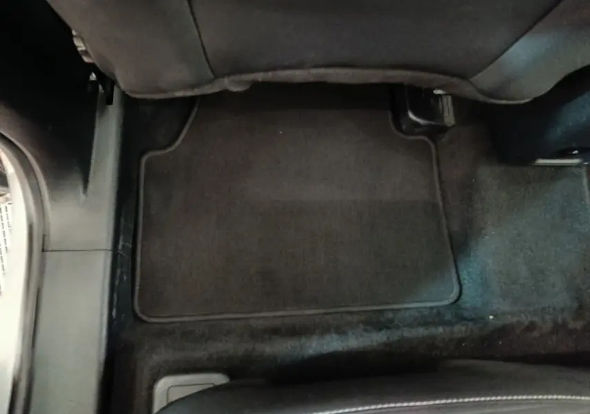 Vue intérieure du plancher arrière avec tapis noir du Ford Kuga 2023 gris foncé, côté droit sous le siège passager.