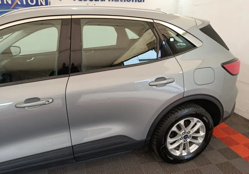 Vue latérale côté droit du Ford Kuga gris foncé 2023, mettant en valeur les portes arrière et la roue arrière.