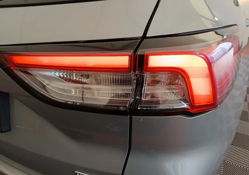 Gros plan sur le feu arrière droit allumé du Ford Kuga gris foncé hybride 2023, avec badge Hybrid visible.