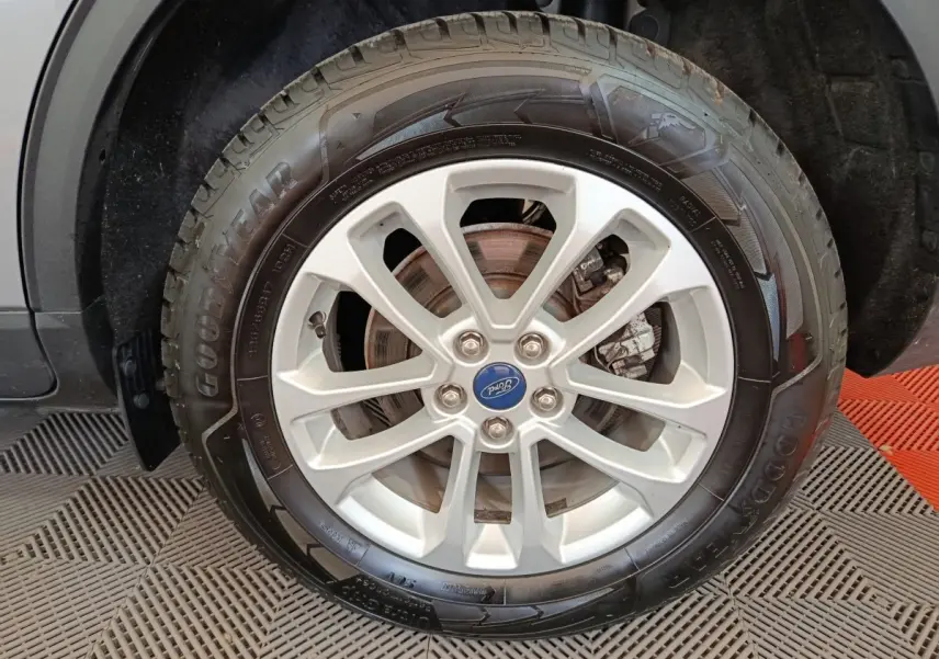Gros plan sur la roue avant droite d’un Ford Kuga gris foncé, avec jante alliage et pneu Goodyear visible.