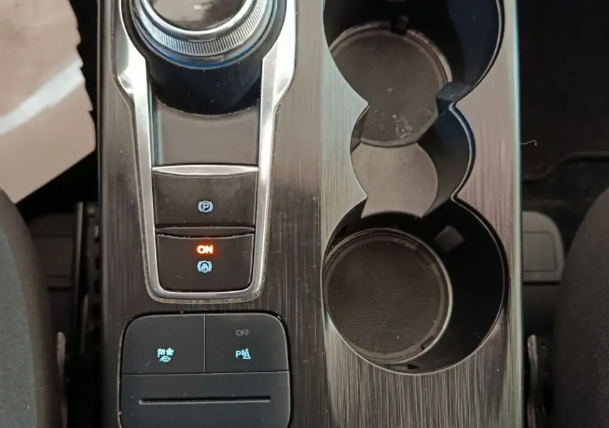 Vue plongeante sur la console centrale noire du Ford Kuga 2023 avec molette de boîte auto et porte-gobelets.