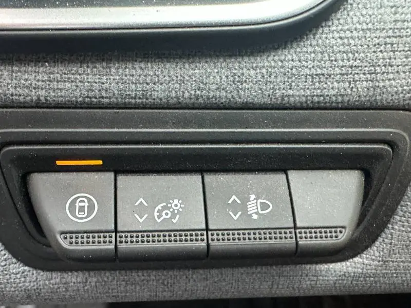 Gros plan sur les boutons de réglage intérieur de la Renault Clio 1.0 TCe 90ch Evolution 2025, avec témoin orange allumé.