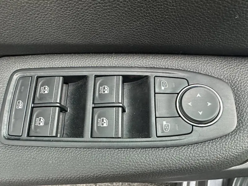Gros plan sur les commandes de lève-vitres et réglage des rétroviseurs noirs dans une Renault Clio 2025.