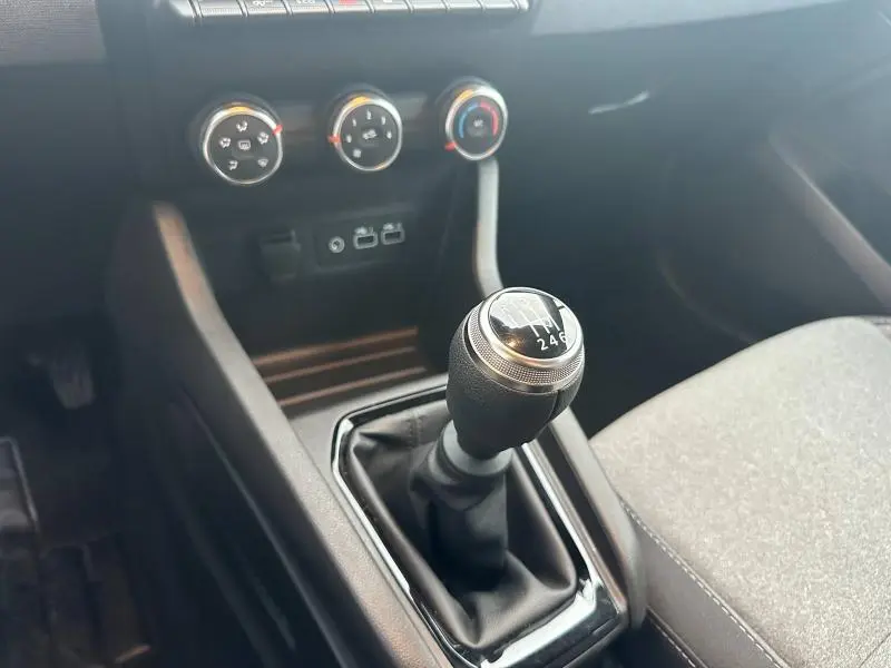 Gros plan sur le levier de vitesses manuel noir de la Renault Clio 2025, avec commandes de climatisation en arrière-plan.