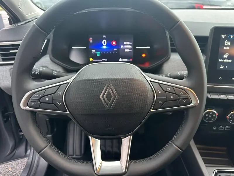 Vue rapprochée du volant noir de la Renault Clio 2025 avec commandes intégrées et tableau de bord numérique allumé.