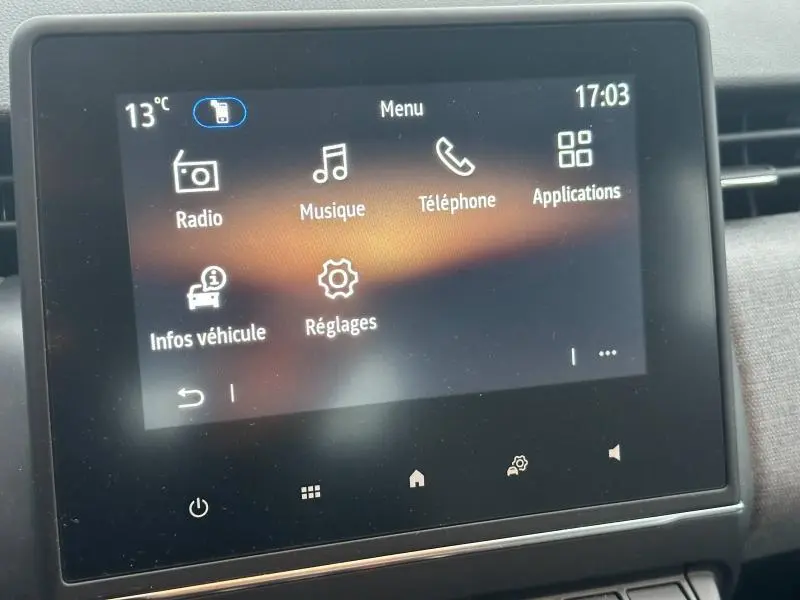 Écran tactile central de la Renault Clio 2025 affichant le menu principal avec icônes radio, musique, téléphone et réglages.