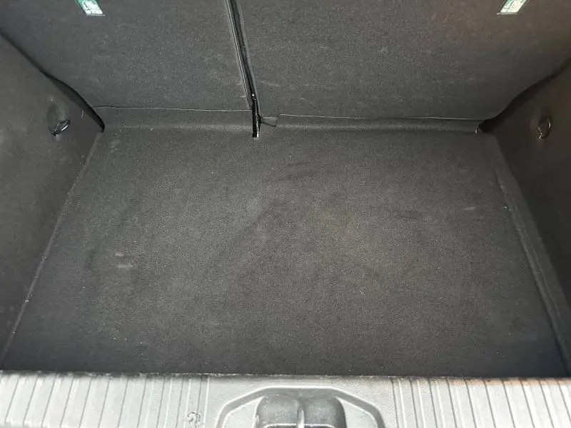 Vue plongeante sur le coffre vide de la Renault Clio 2025, intérieur noir avec tapis en tissu.
