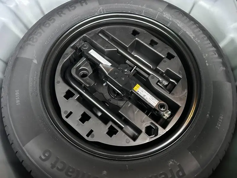Roue de secours avec kit de démontage noir, vue en plongée au centre du coffre d’une Renault Clio 2025.