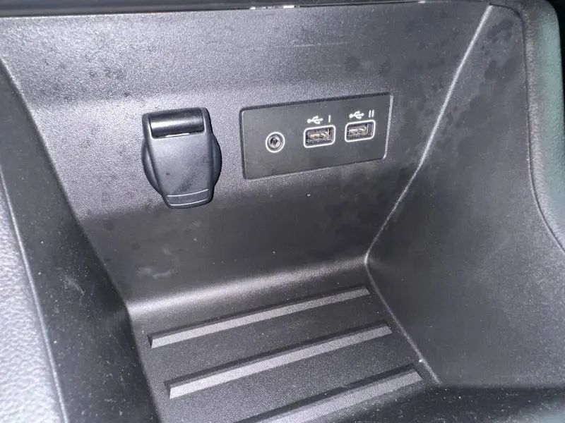 Gros plan sur la console centrale noire de la Renault Clio 2025 montrant deux ports USB et une prise auxiliaire.