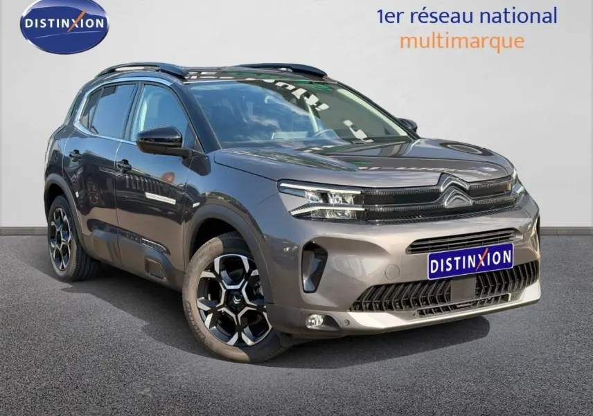 Citroën C5 Aircross gris Platinium vue 3/4 avant droit avec jantes alu et barres de toit visibles.