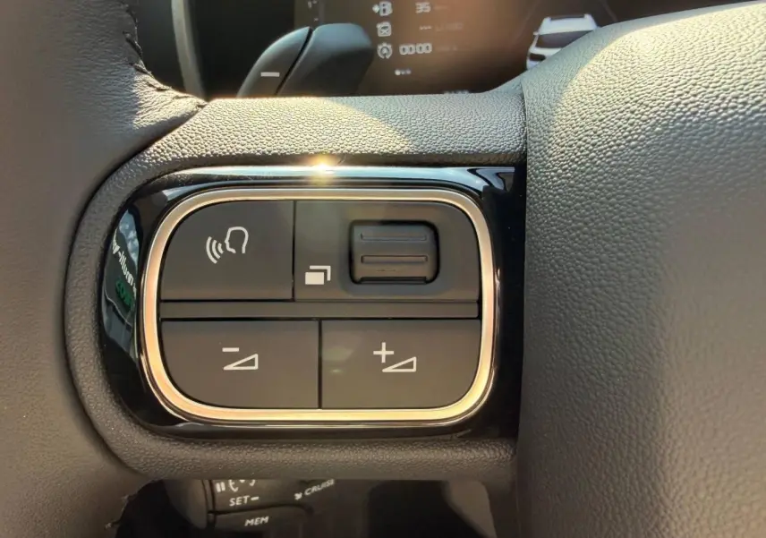 Gros plan sur les commandes vocales et volume au volant cuir du Citroën C5 Aircross gris Platinium 2025.