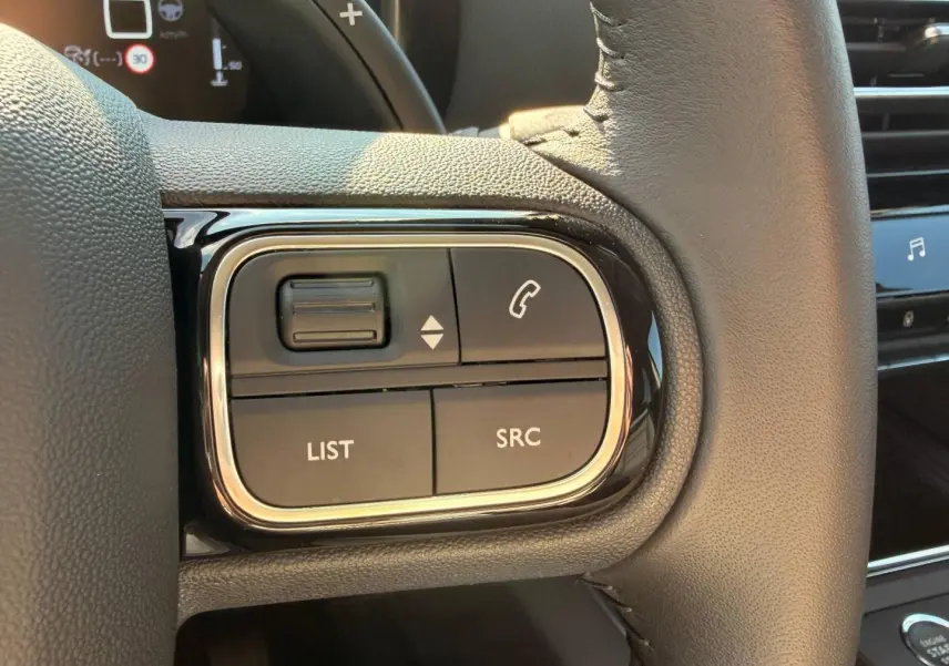 Gros plan sur les commandes gauche du volant cuir noir du Citroën C5 Aircross 2025, avec boutons SRC et LIST visibles.