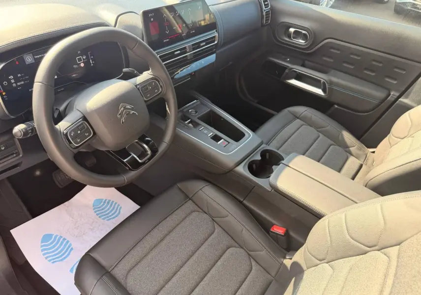 Intérieur avant du Citroën C5 Aircross 2025, vue côté conducteur, sièges tissu noir et tableau de bord moderne.