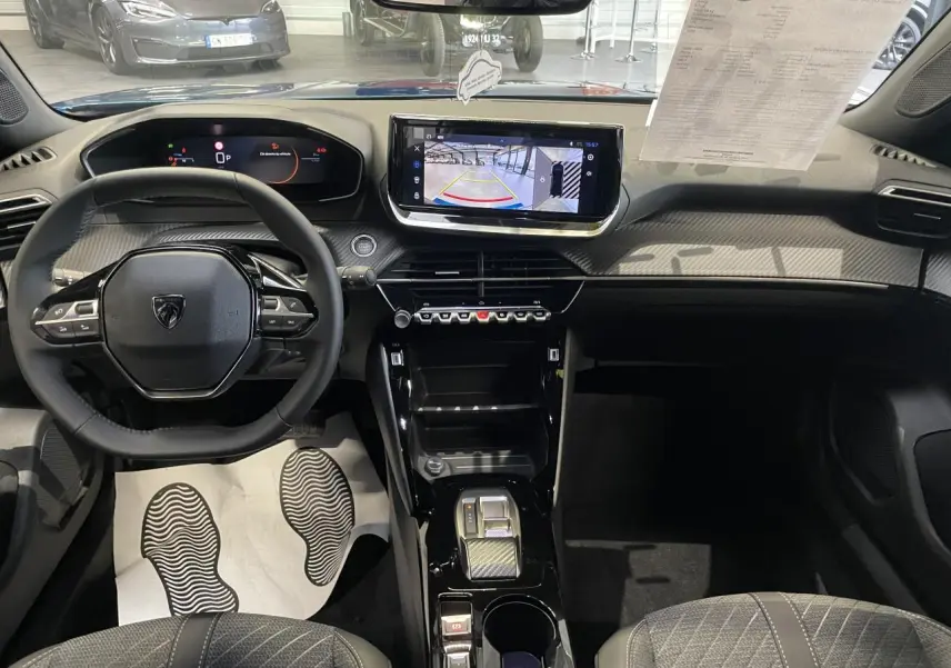 Vue intérieure avant du Peugeot 2008 2026, tableau de bord noir avec écran tactile et volant compact cuir.