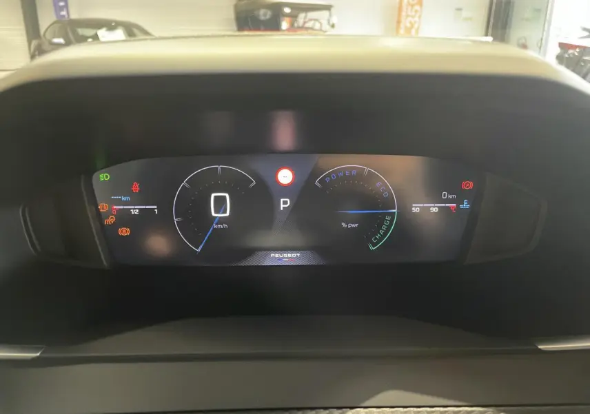 Tableau de bord numérique du Peugeot 2008 hybride affichant la vitesse, la puissance et les indicateurs de charge en vue frontale.
