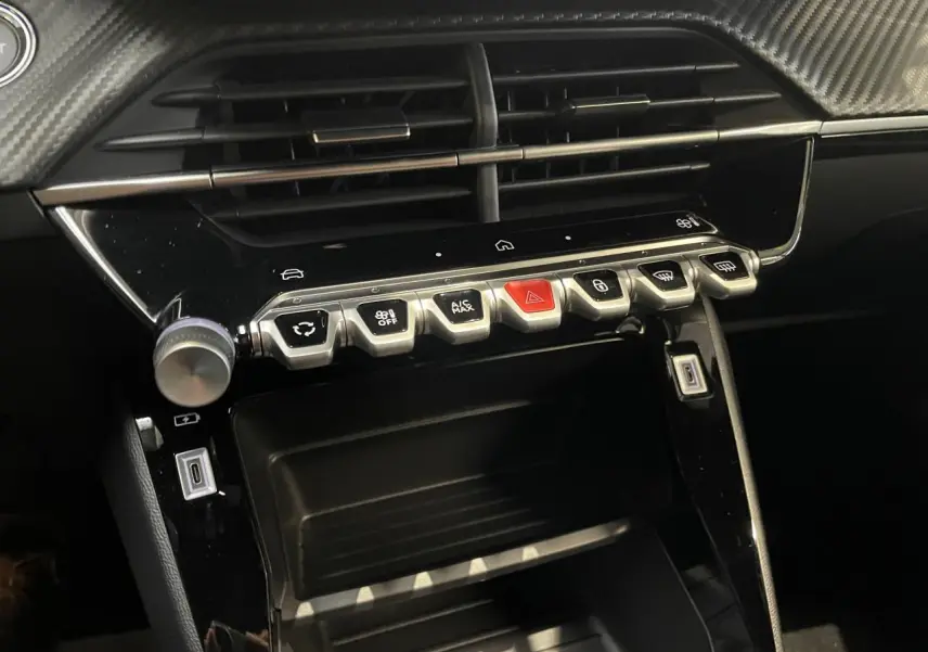 Détail de la console centrale noire brillante du Peugeot 2008 Hybrid 2026 avec boutons de commande et prises USB.
