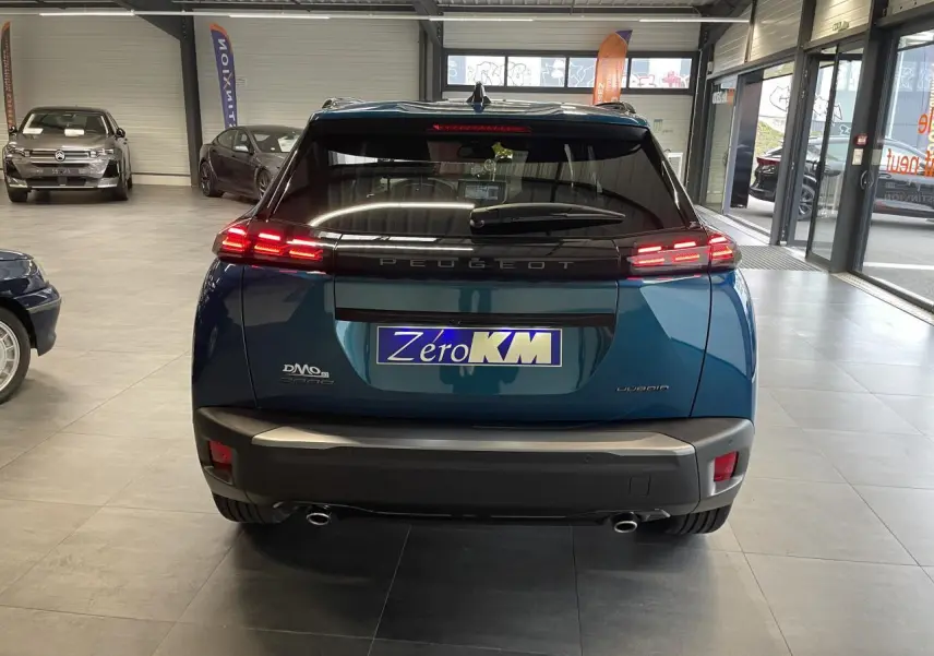 Vue arrière d'un Peugeot 2008 bleu avec feux arrière LED 3 griffes et double sortie d'échappement chromée.